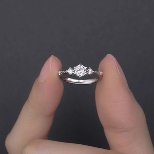 Elegant three-stone zircon ring with silver braided band texture on a dark background