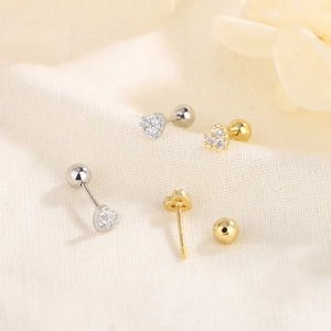 Exquisite gold and silver heart screw-back earrings with zircon on a soft beige fabric