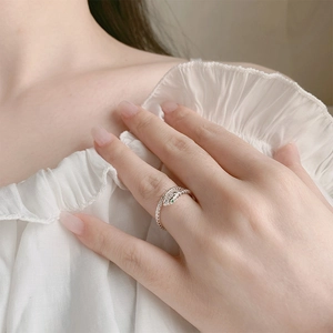Elegant silver snake ring with green gem eyes worn by a model in a soft minimalist style