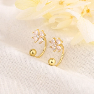 Exquisite 18K gold four-leaf clover stud earrings with pink heart crystals on linen