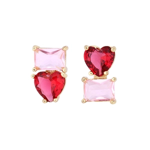 Détail de boucles d'oreilles asymétriques en or avec cristal rose et cœur rouge