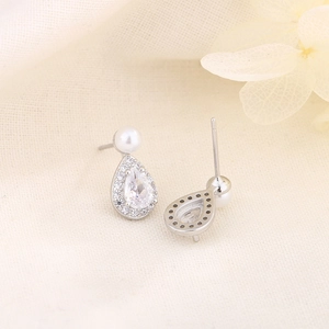 Boucles d'oreilles perles en goutte d'eau avec zircons sur un fond en tissu beige