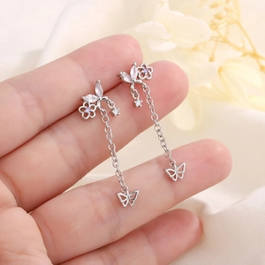 Boucles d'oreilles papillon en argent avec zircons mauves tenues à la main