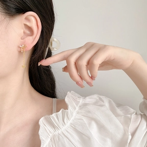 Boucles d'oreilles papillon dorées avec fleurs mauves et longue chaîne sur le mannequin
