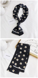 Détail macro d'un foulard en soie noir avec imprimé marguerites et bords rayés