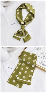 Gros plan du foulard étroit en soie vert avocat avec imprimé marguerites blanches et brillant