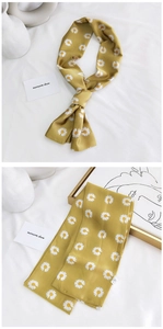 Détail d'un foulard étroit jaune avec motif floral de marguerites sur fond blanc épuré