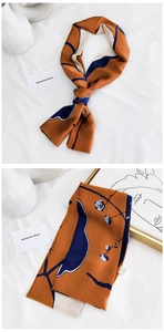 Détail d'un foulard en soie artistique montrant des motifs floraux orange et marine