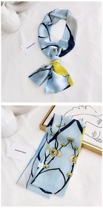 Détail d'un foulard étroit bleu clair avec des fleurs de prunier et texture soie