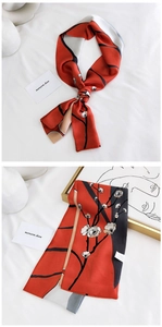 Détail d'une écharpe étroite rouge et noire avec motifs de fleurs de prunier et soie