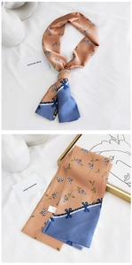 Détail de l'écharpe en soie orange élégante avec motifs floraux et bordures bleues