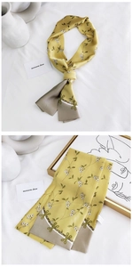 Détail d'un foulard étroit en soie jaune avec motifs floraux et texture satinée