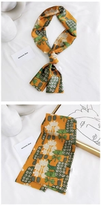 Détail d'un foulard étroit orange à fleurs montrant l'imprimé et la texture soie