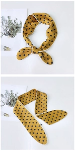 Close-up of yellow polka dot silk scarf with smooth texture and delicate white stitching