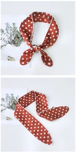 Detailed view of red silk neckerchief with white polka dots and elegant white piping