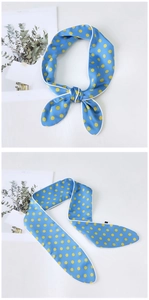 Close-up of bright blue silk scarf with yellow polka dots and fine white border
