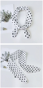 Detailed view of polka dot silk scarf tied in a bow and laid flat against a white backdrop