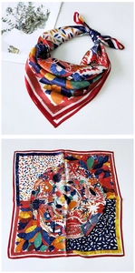 Detail view of square silk scarf with red border and intricate botanical print pattern