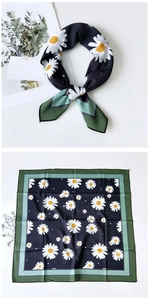 Detail of square silk scarf with navy daisy print and green geometric border folded neatly