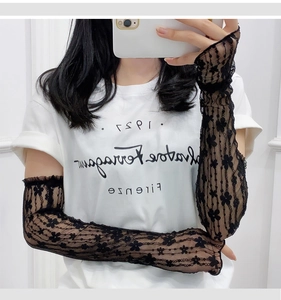 Detail of black lace sun protection sleeves with delicate floral embroidery and ruffled cuffs