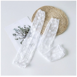 Detail of white floral lace over-the-knee socks with elegant ruffled edges on a mat