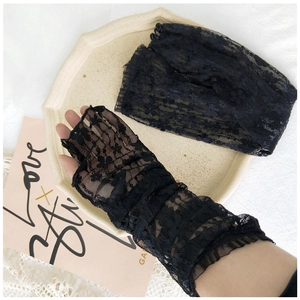 Close-up of black floral lace arm sleeves with ruffle wrist trim on an elegant tray
