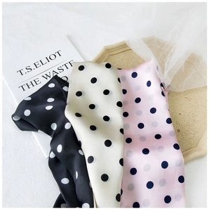 Close-up of elegant polka dot silk scarves in black, cream, and pink with a satin finish
