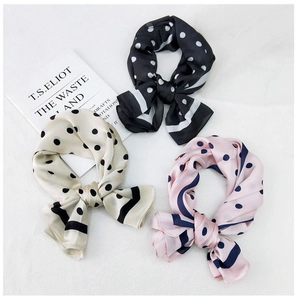 Detailed view of three polka dot satin scarves in black, cream, and pink with contrast edges