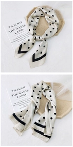 Detailed view of polka dot silk scarf featuring classic black dots and striped border edges
