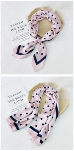 Close-up of pink polka dot silk scarf featuring navy blue borders and soft texture