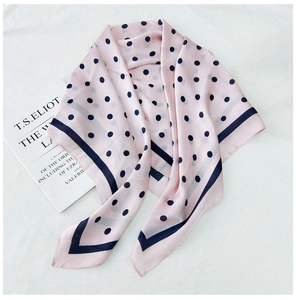 Detail of pink polka dot silk scarf draped over books for a retro elegant aesthetic