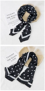 Detailed view of elegant black silk scarf with white polka dots and stylish border
