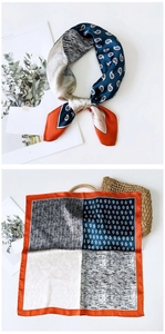 Detail eines Seidenschals mit blauem Paisley-Muster und orangefarbenem Randakzent