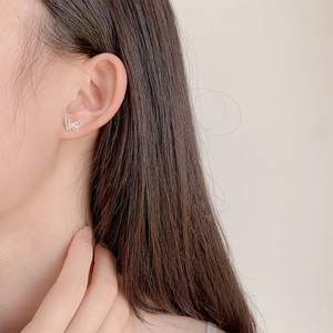 Delicate silver butterfly stud earrings with colorful cubic zirconia on model's ear