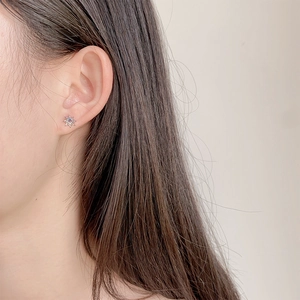 Elegant sun-shaped stud earring with blue gemstone on model showing dainty aesthetic