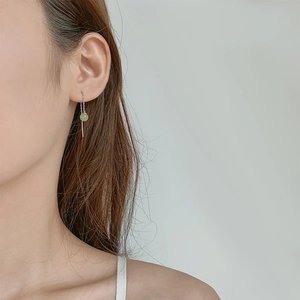 Elegant long silver drop earrings with light green jade bead shown on a female model