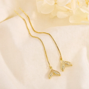 Elegant gold fishtail drop earrings featuring cubic zirconia on a white soft fabric background