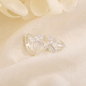 Boucles d'oreilles nœud en argent avec zircons rectangulaires sur tissu en lin