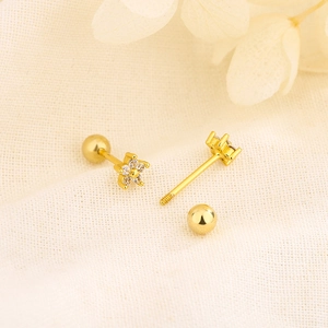 Elegant gold flower stud earrings with zircon inlay and screw back on white fabric