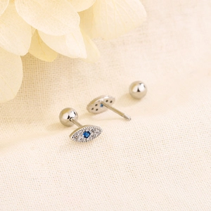 Mini silver Evil Eye stud earrings with blue stones and screw backs on beige fabric