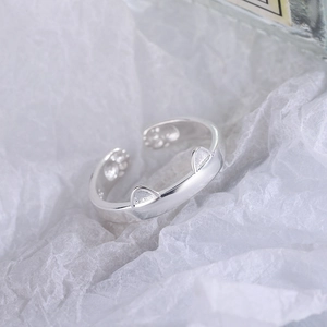 Cute silver cat ear open ring with paw print details on minimalist white paper background