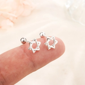 Star-shaped silver screw back earrings featuring a hollow hexagram design on a fingertip