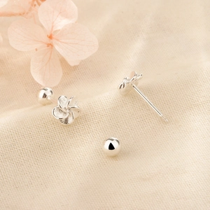 Boucles d'oreilles fleurs en argent avec fermoir à vis sur un fond en tissu minimaliste
