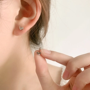 Minimalist 925 sterling silver heart stud earrings with screw back on model's ear
