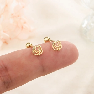 Elegant gold hollow rose stud earrings with screw ball back closure on fingertip