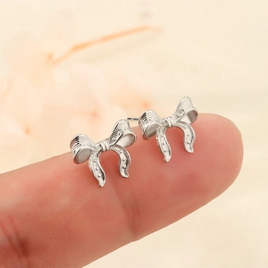 Orecchini a perno a fiocco in argento con texture mostrati sulla punta del dito