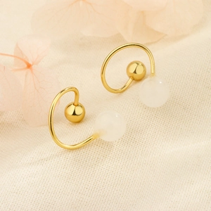 Boucles d'oreilles spirales dorées avec perles d'opale et fermoir à vis sur fond tissu