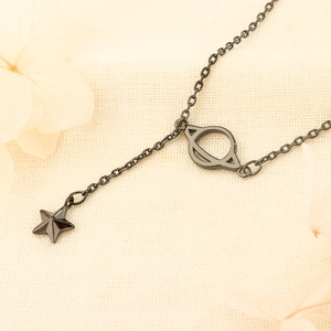 Star and Saturn pendant necklace in gunmetal black finish on minimalist beige texture