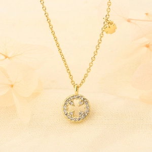 Gold-plated clover necklace with sparkling zircon-encrusted round cross pendant on beige fabric