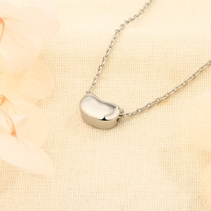 Elegant silver bean pendant necklace on a minimalist cross chain with a polished finish